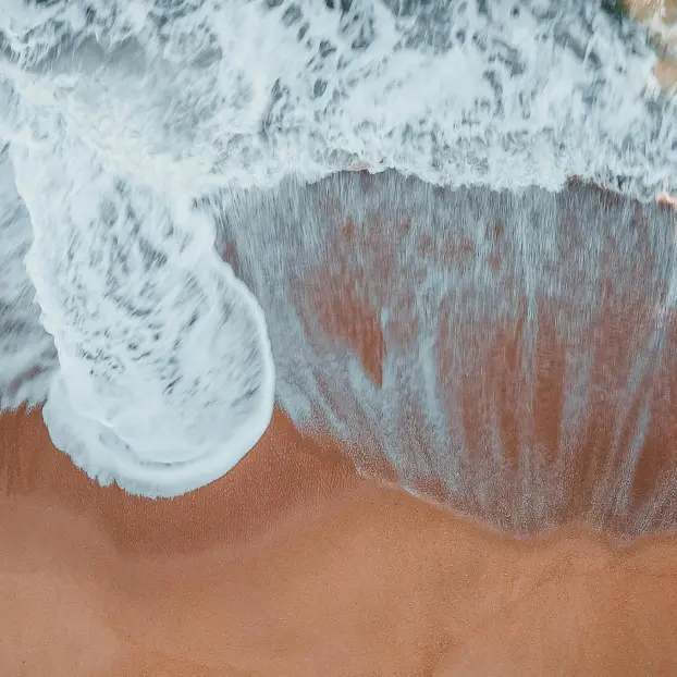 Ruhige Wellen treffen auf den Sandstrand – dekoratives Stimmungsbild im FAQ-Bereich des Wellenkraft Programms.